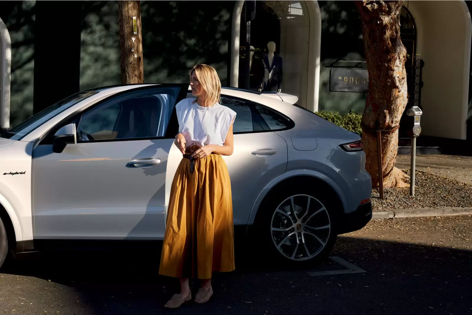 Una chica de pie frente a un SUV blanco con Seguro de Auto visto de costado