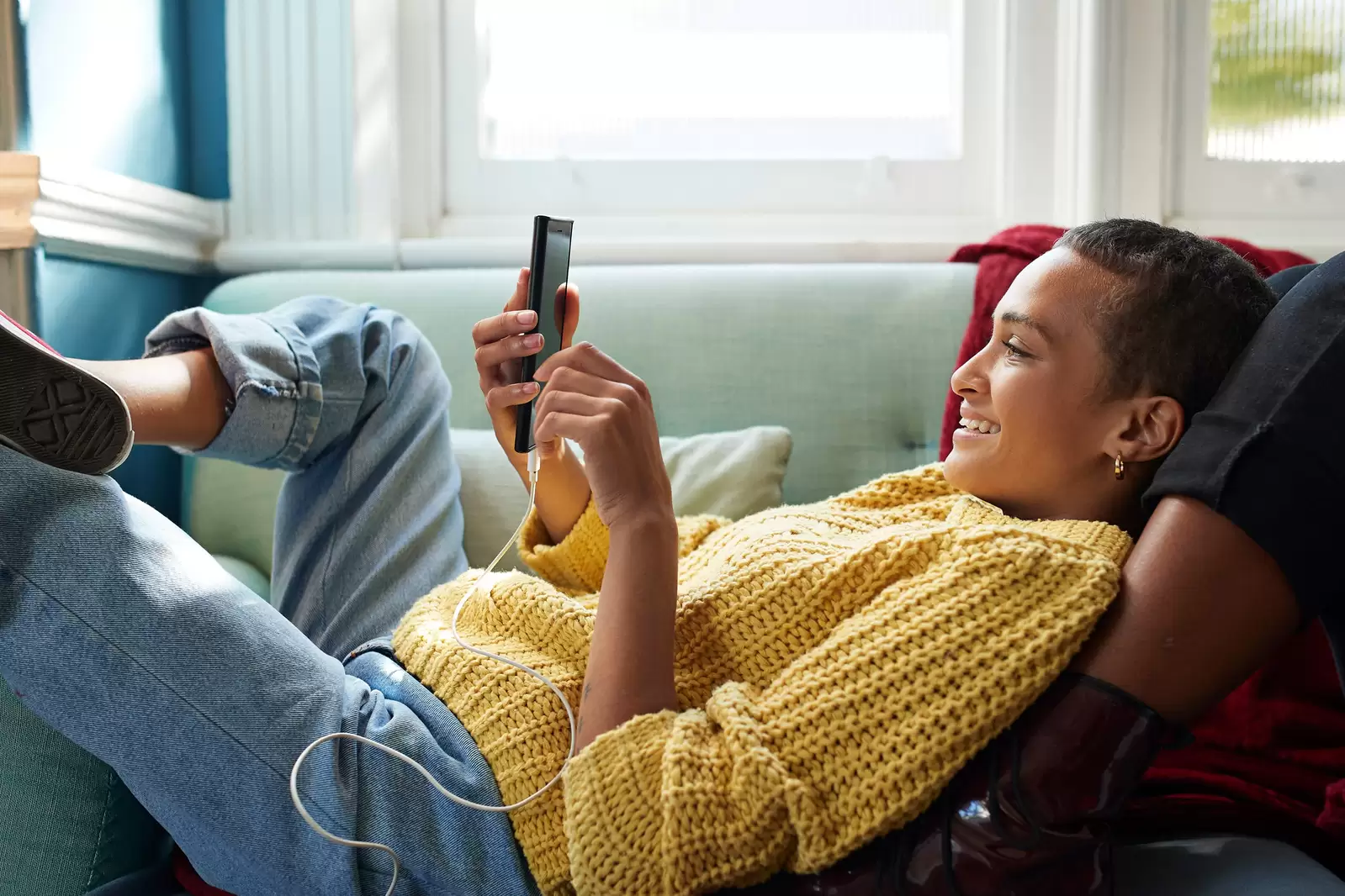 Mujer joven tumbada en un sofá mirando un móvil