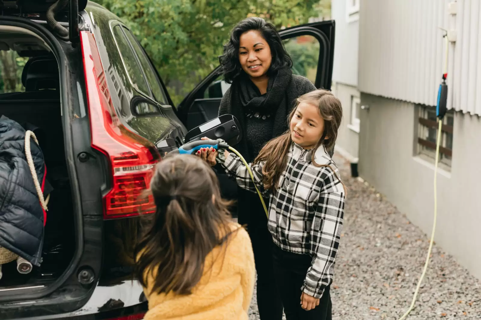 Una madre con sus hijas cargando un coche eléctrico de Renting en casa