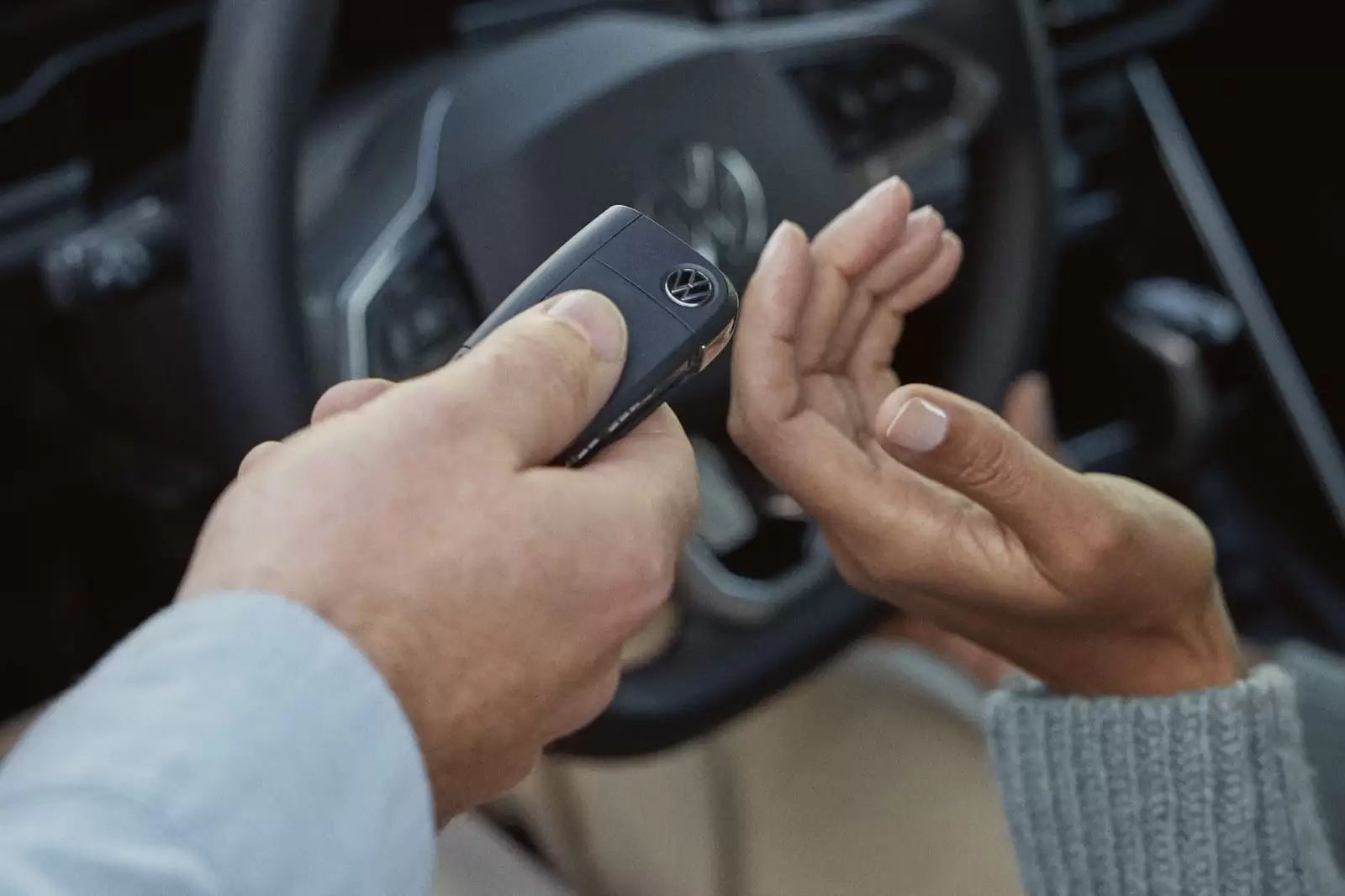 Detalle de una mano pasando una llave a otra en un coche con seguro de garantía
