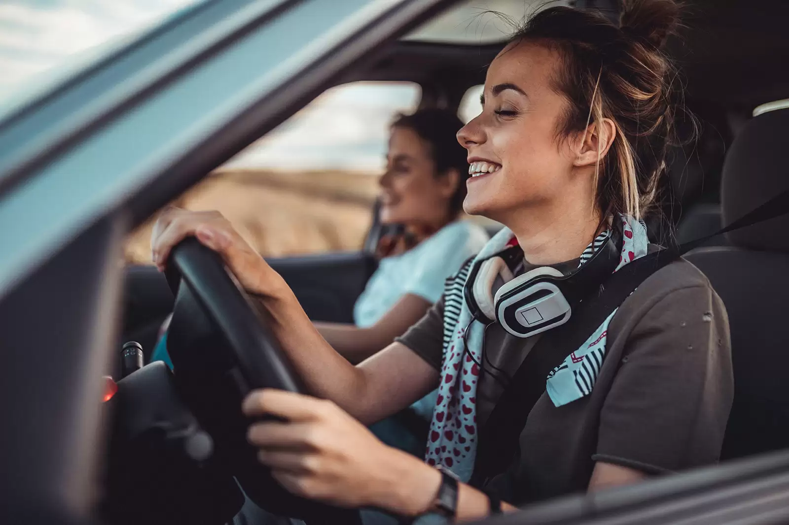 Chicas jóvenes sonriendo dentro de un coche vistas a través de la ventanilla