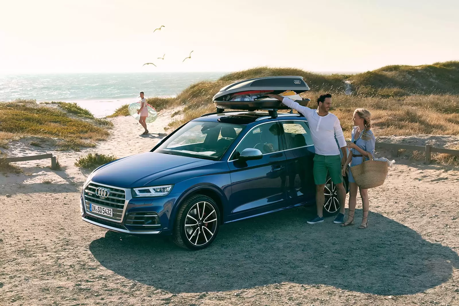Una pareja con un coche de alquiler del Grupo Volkswagen, Rent-a-Car en la playa 