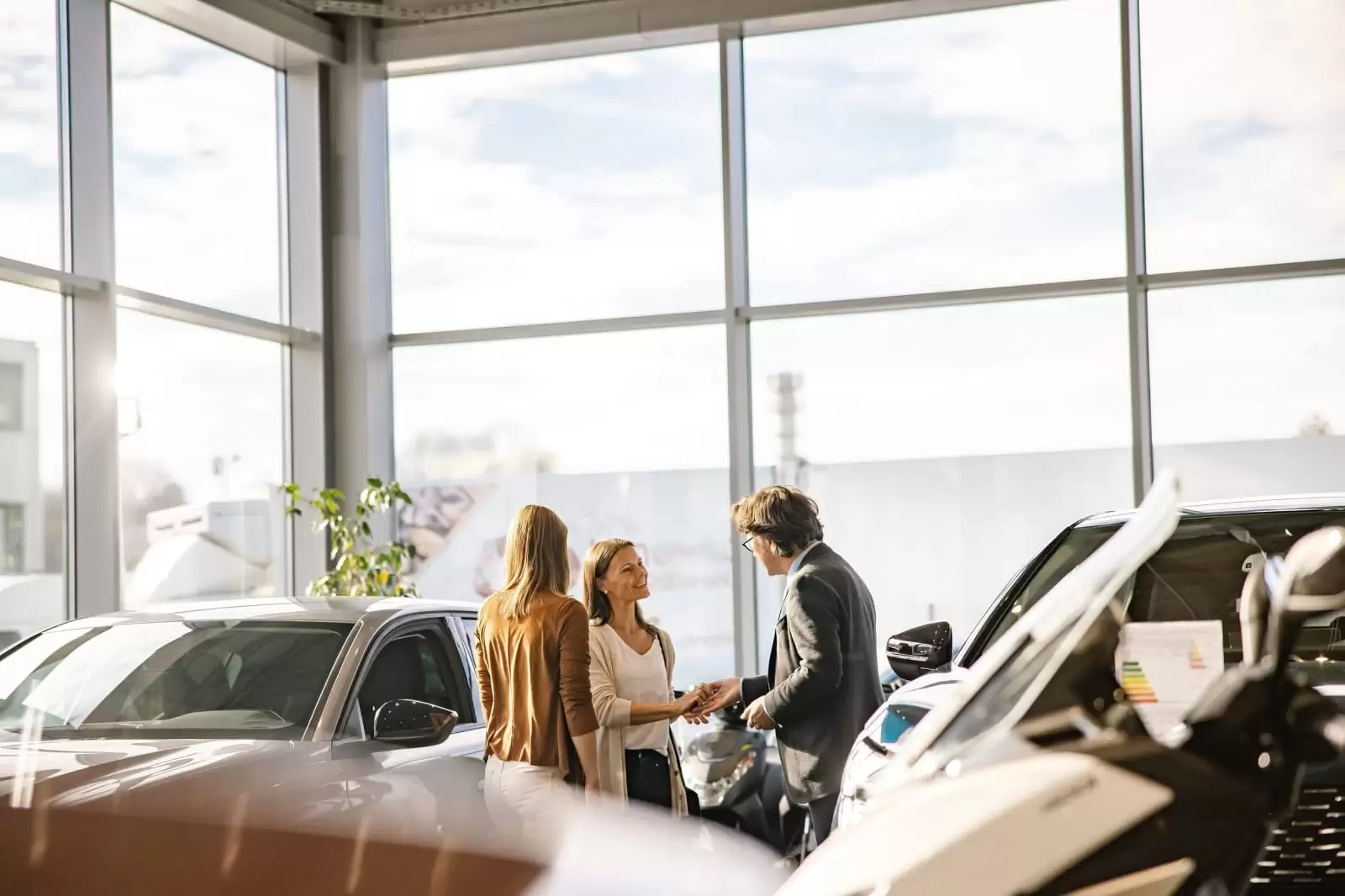 Una mujer habla con un asesor comercial que le muestra un coche de renting flexible empresas en un concesionario del Grupo Volkswagen