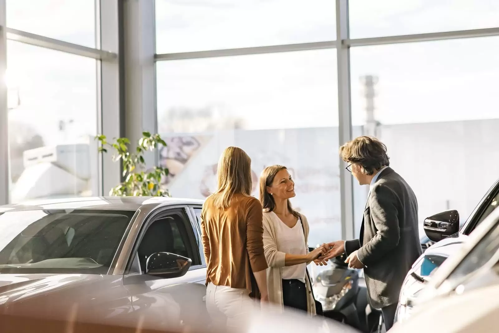 Una mujer habla con un asesor comercial que le muestra un coche de renting flexible empresas en un concesionario del Grupo Volkswagen