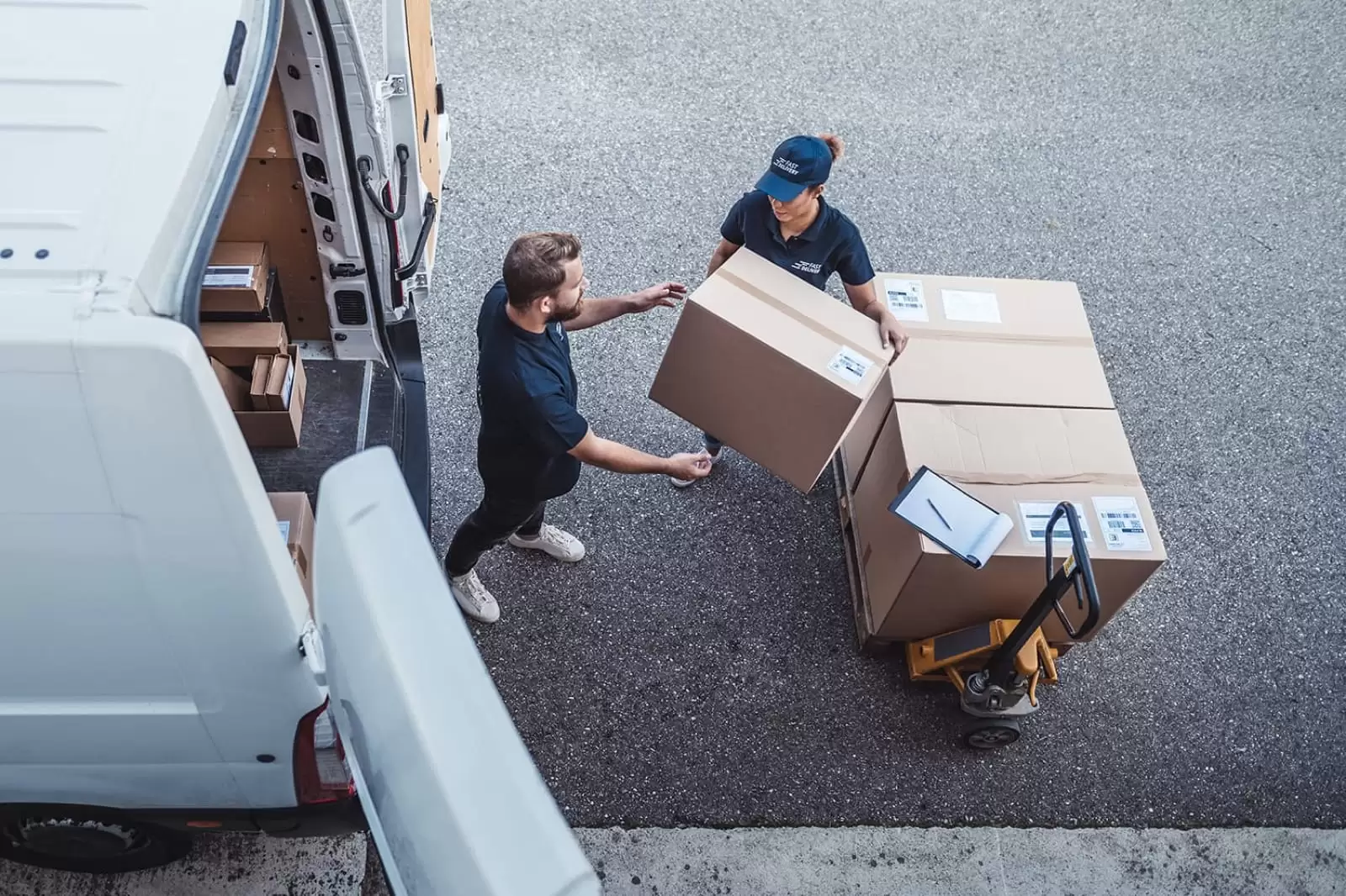 Vista desde arriba de un hombre y una mujer sacado un paquete de una furgoneta de renting del Grupo Volkswagen