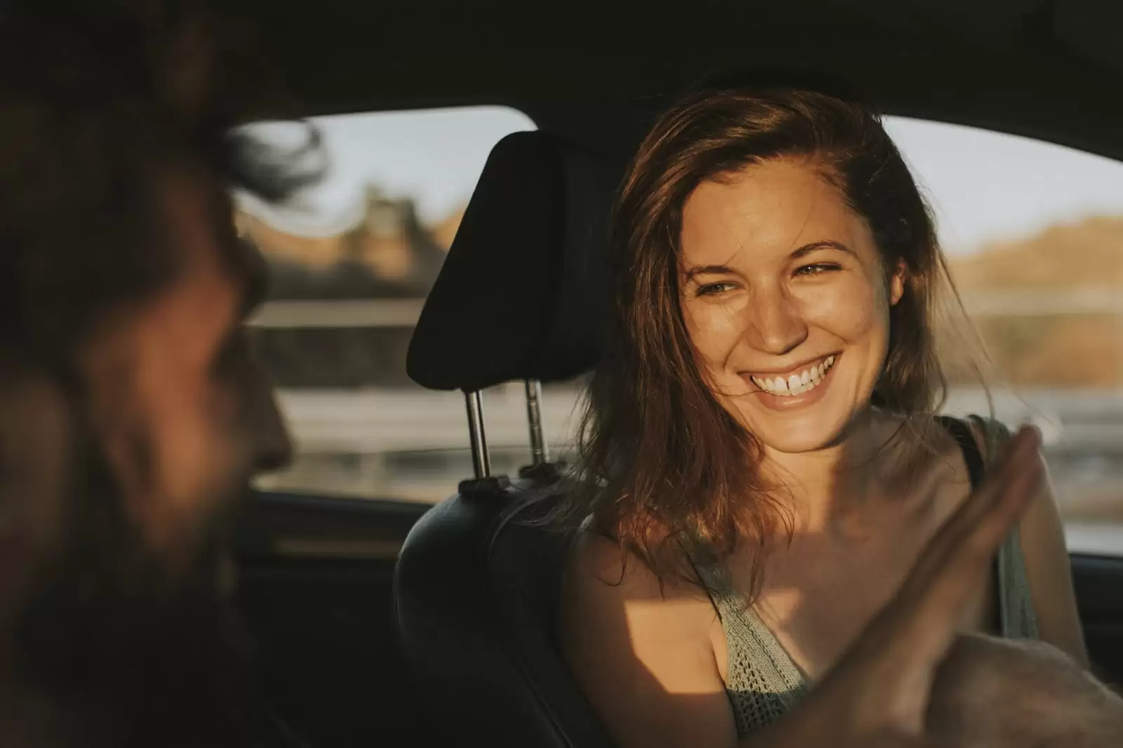 Una chica sonriendo sentada al volante de un coche de Renting