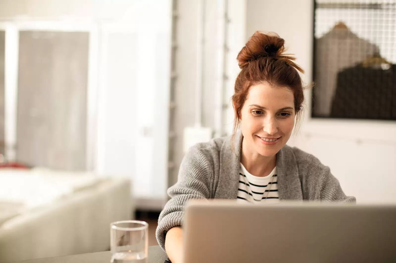 Mujer sonriendo delante de un ordenador en casa